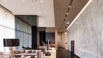 Eine moderne Lobby mit Marmorwand, einer Couch, einem Fernseher und einem raumhohen Fenster.