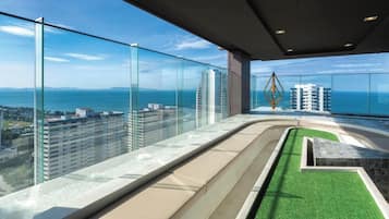 Un immeuble de grande hauteur doté d’un balcon en verre qui offre une vue sur le paysage urbain et une étendue d’eau.