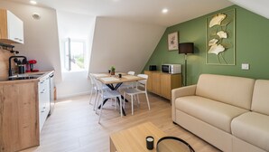 A compact living space with a kitchenette, dining area, and a sofa.