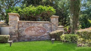 Eine Steinsäule mit einem Schild für 'TUSCANA ORLANDO'S MI DITERRANNEAN INSPIRED GARDEN CONDOMINIUMS'.