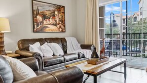 Ein Wohnzimmer mit Ledersofa, einem Gemälde, einer Vase und einem Balkon mit Blick.