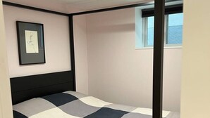 A room with a bed, a framed picture on the wall, and a window.