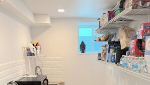 A kitchen with a wooden countertop, a sink, a window, and shelves with various items.