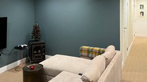 A modern living room with a sectional sofa, a small Christmas tree, and a television.