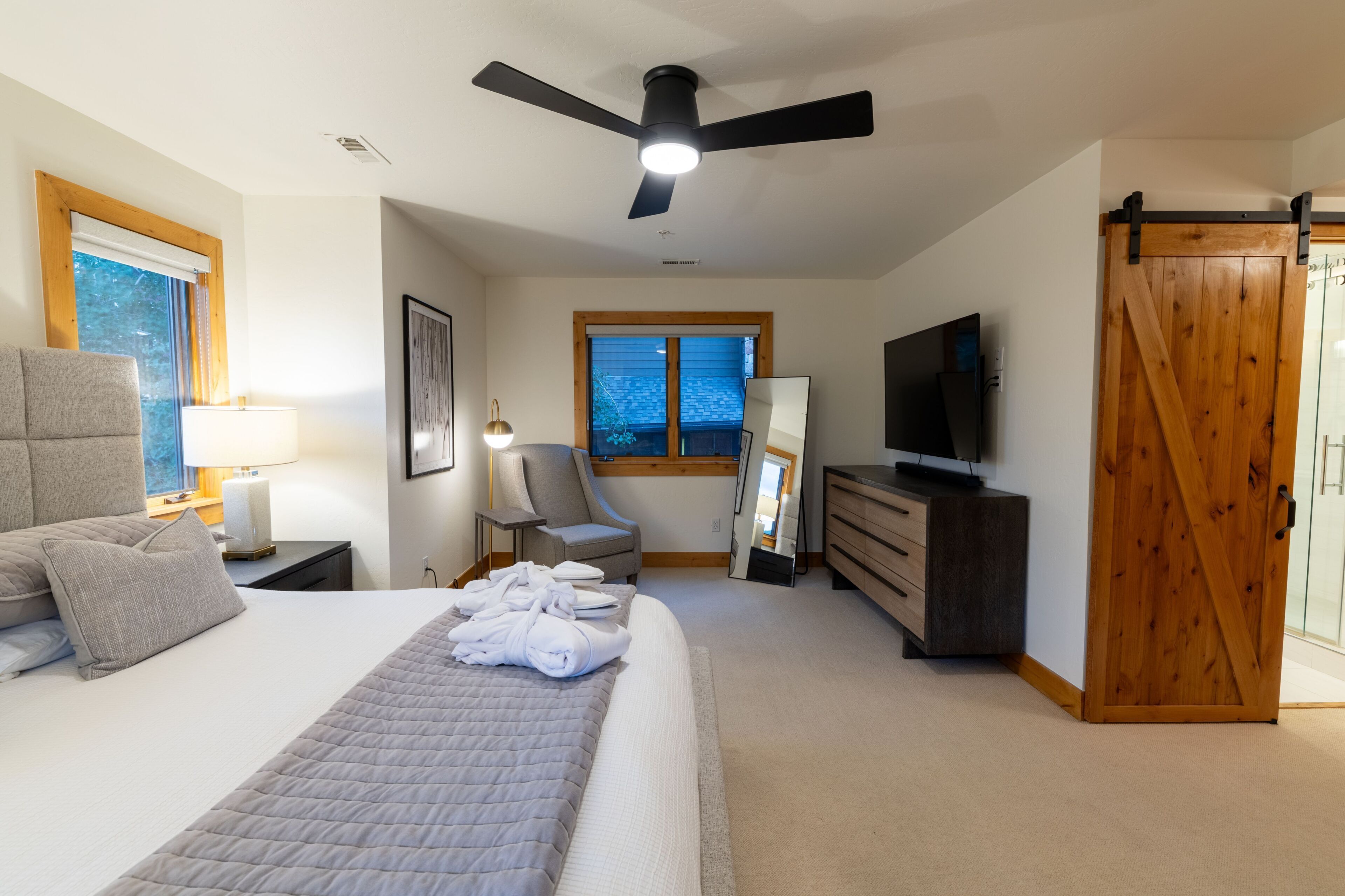 A hotel room with a bed, a desk, a chair, a TV, and a wardrobe.