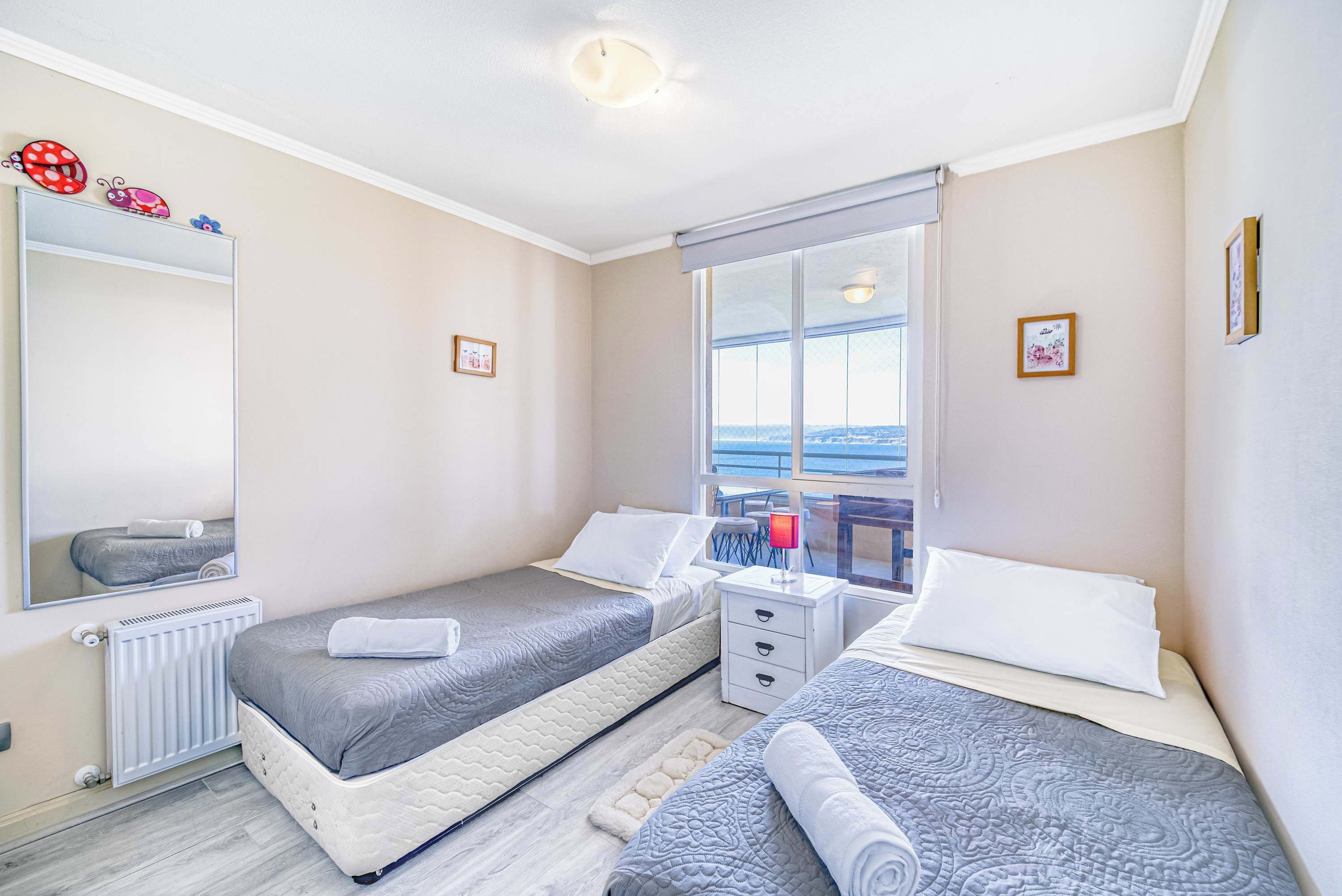 Une chambre avec deux lits, une fenêtre donnant sur un beau paysage, une table de chevet avec une lampe et un radiateur.