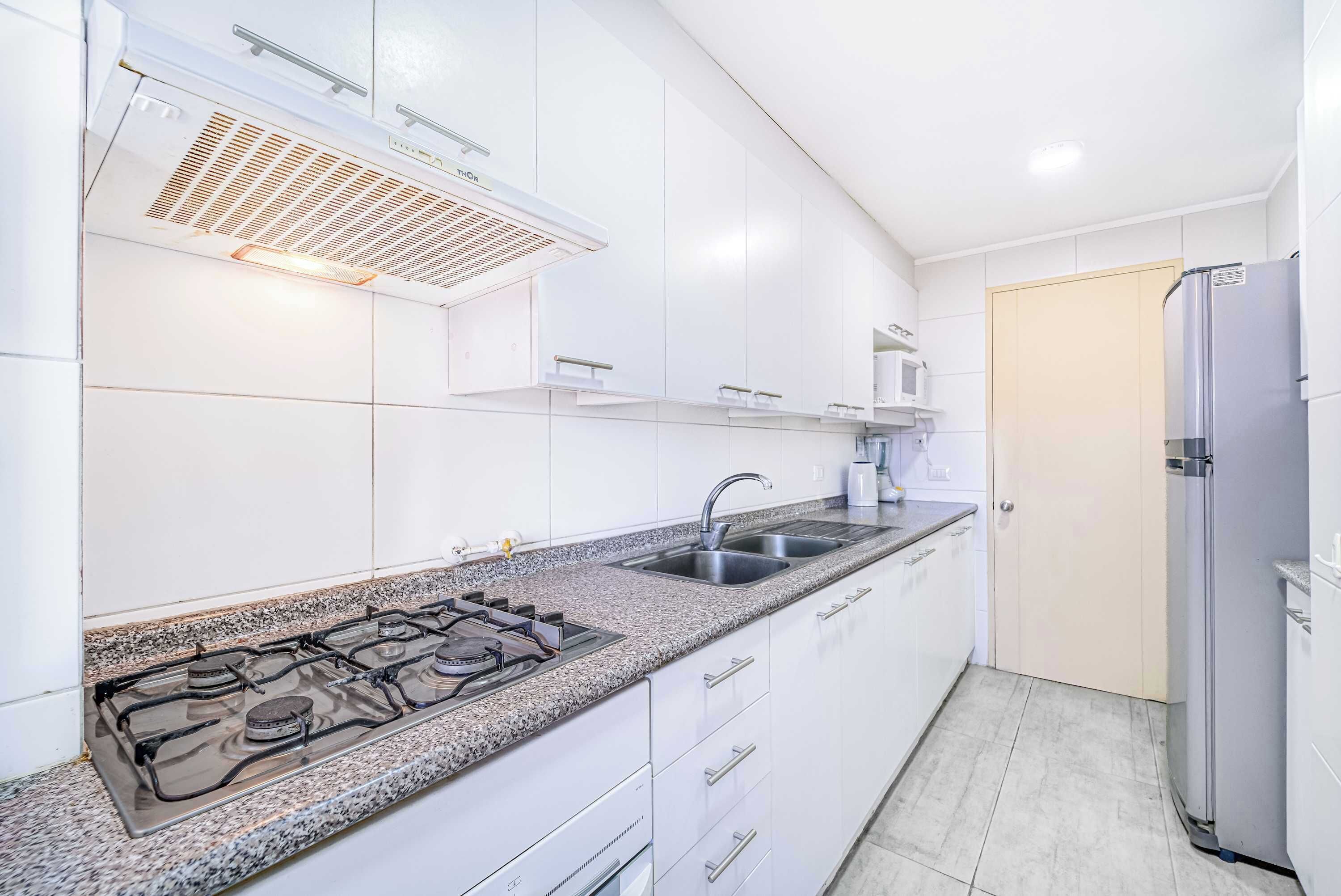 A modern kitchen with white cabinets, a granite countertop, stainless steel appliances, and a built-in range hood.