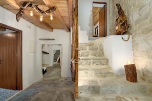 A stone staircase with a wooden handrail, a rustic ceiling with exposed beams, and a wooden door. - Aspasia Wabi Retreat by CVR (Roustika)