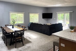 A living room with a dark-colored sofa, a dining table with chairs, and a flat-screen TV mounted on the wall. - Dells Lakeside Lodge - Wisconsin Dells. (Lyndon Station)