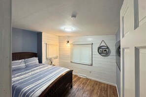 A bedroom with a bed, a wall-mounted shelf, and a window with blinds. - Dells Lakeside Lodge - Wisconsin Dells. (Lyndon Station)