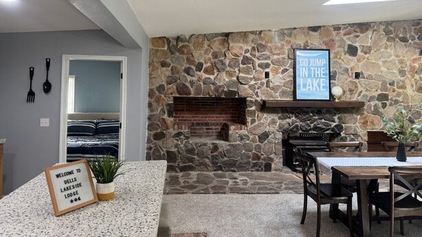 A stone fireplace, a welcome sign, and a dining area with chairs and a table. - Dells Lakeside Lodge - Wisconsin Dells. (Lyndon Station)