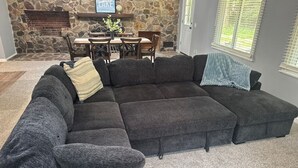 A sectional sofa with a stone fireplace and a dining area in the background. - Dells Lakeside Lodge - Wisconsin Dells. (Lyndon Station)