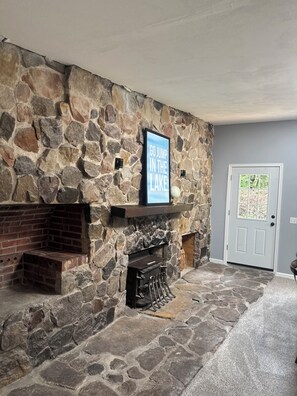A stone fireplace with a sign above it, a door to the right, and a stone floor. - Dells Lakeside Lodge - Wisconsin Dells. (Lyndon Station)