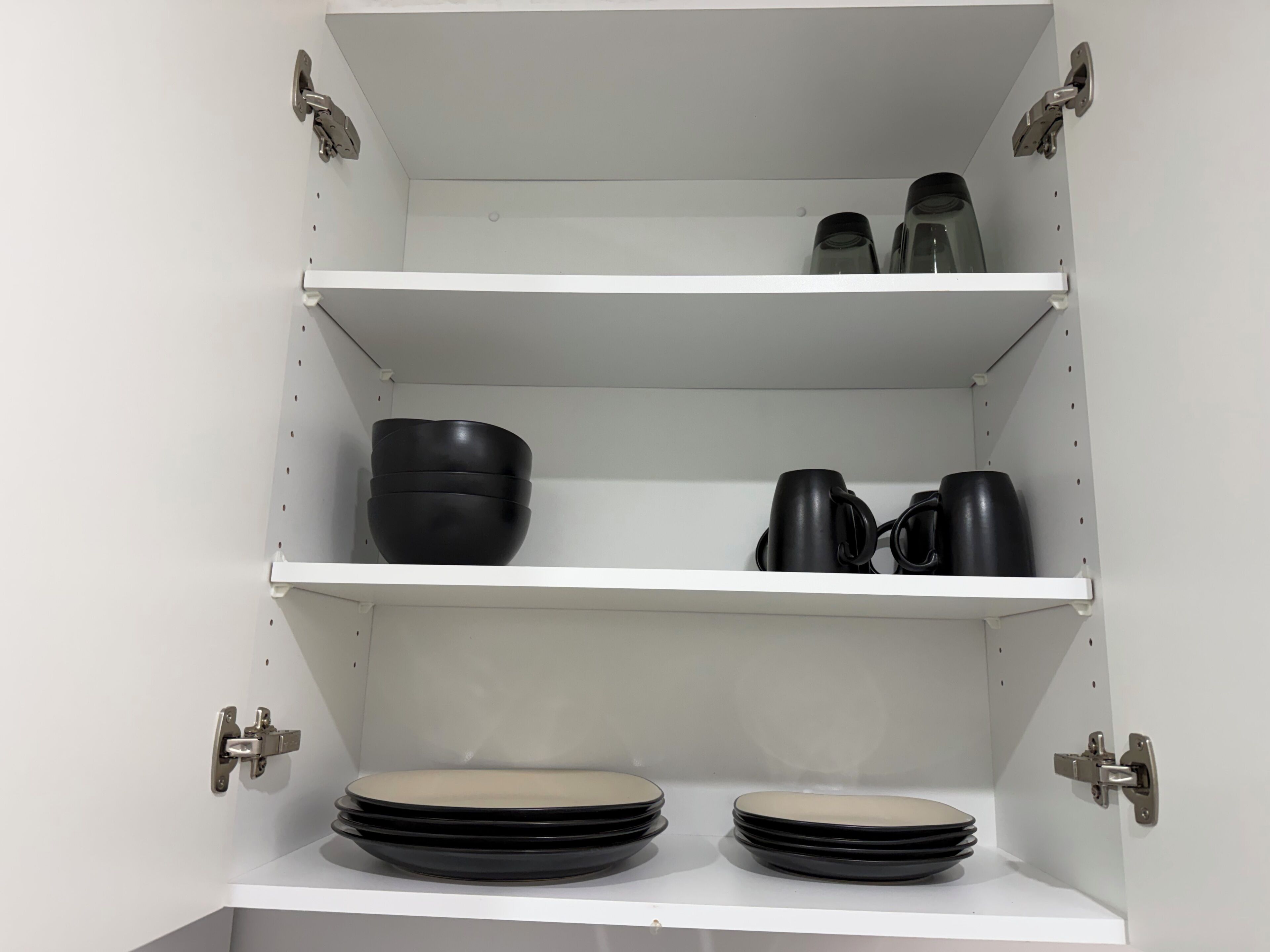 A white cabinet with three shelves, each holding different kitchenware items.