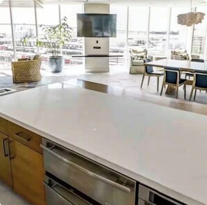 A modern kitchen with a large island, built-in appliances, and a view of the city. - 2BD/2BR High Rise Condo. In the Heart of Downtown SD (San Diego)