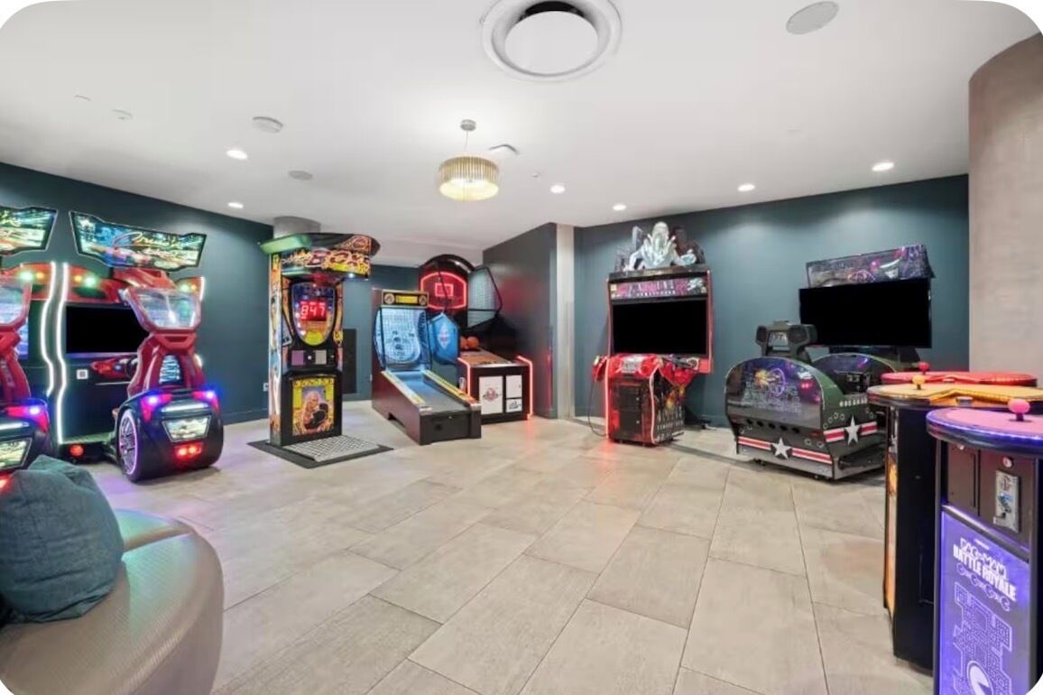 A room with arcade games, a sofa, and a television.
