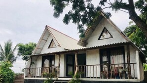 Una casa de dos pisos con un balcón, una escalera que conduce a la entrada y un camino de grava.