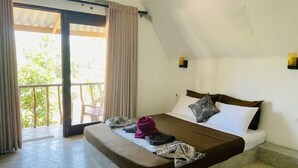 Un dormitorio con cama, cortinas y vistas a través de un ventanal.