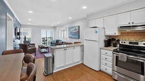 Una cocina moderna con gabinetes blancos, un horno de acero inoxidable y un refrigerador.