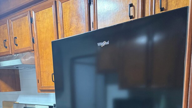 Una cucina con mobili in legno, un piano cottura in acciaio inossidabile e un frigorifero nero.