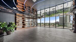 Un vestíbulo amplio con un gran muro de cristal, estanterías modernas y plantas en macetas.