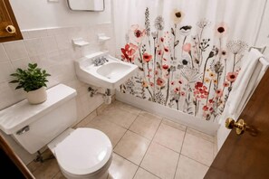 A bathroom with a toilet, sink, and shower curtain with floral patterns.