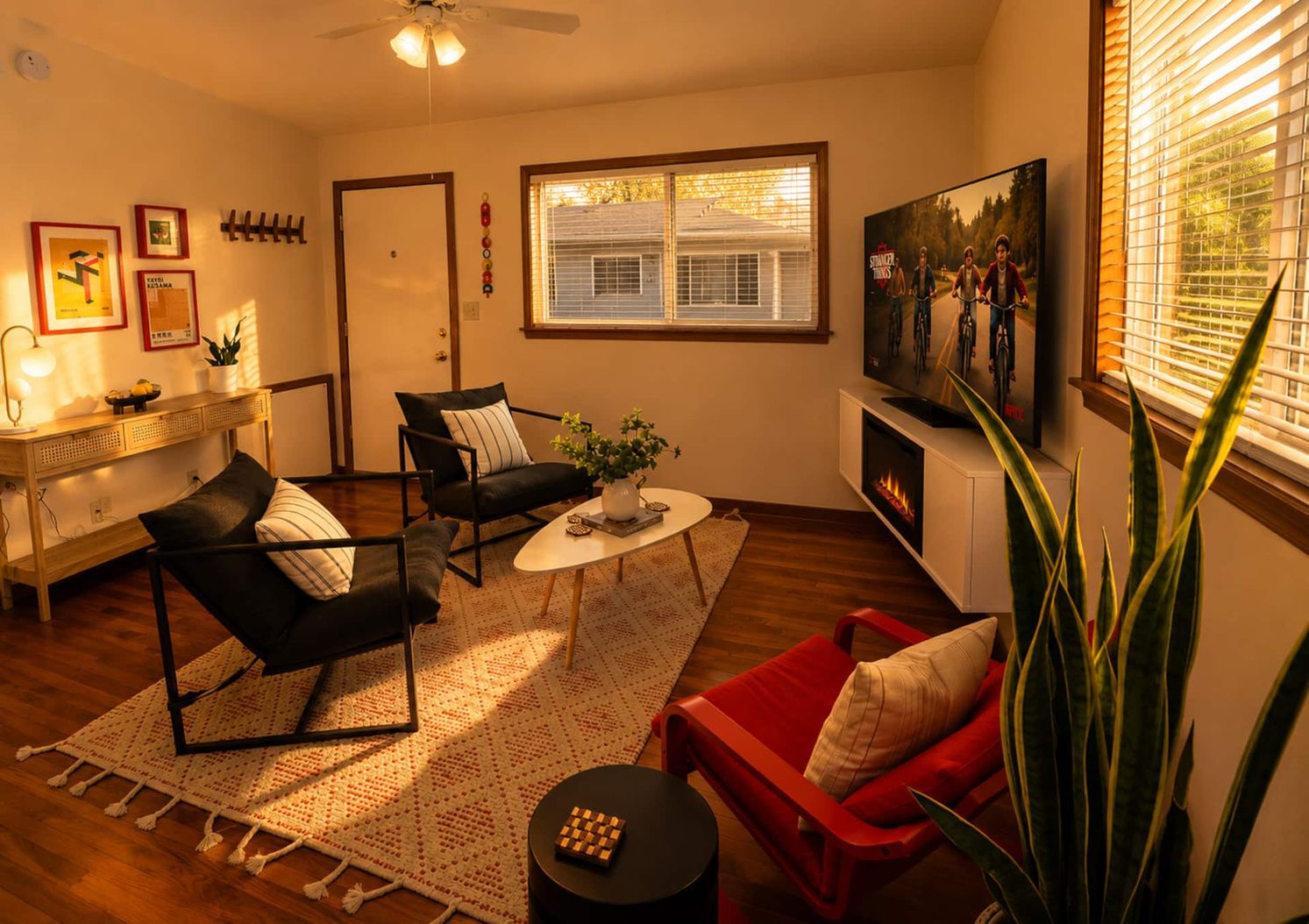 A living room with a fireplace, a television, and a large window with blinds.