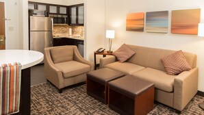A living room with a sofa, armchair, coffee table, and a small table with a lamp.