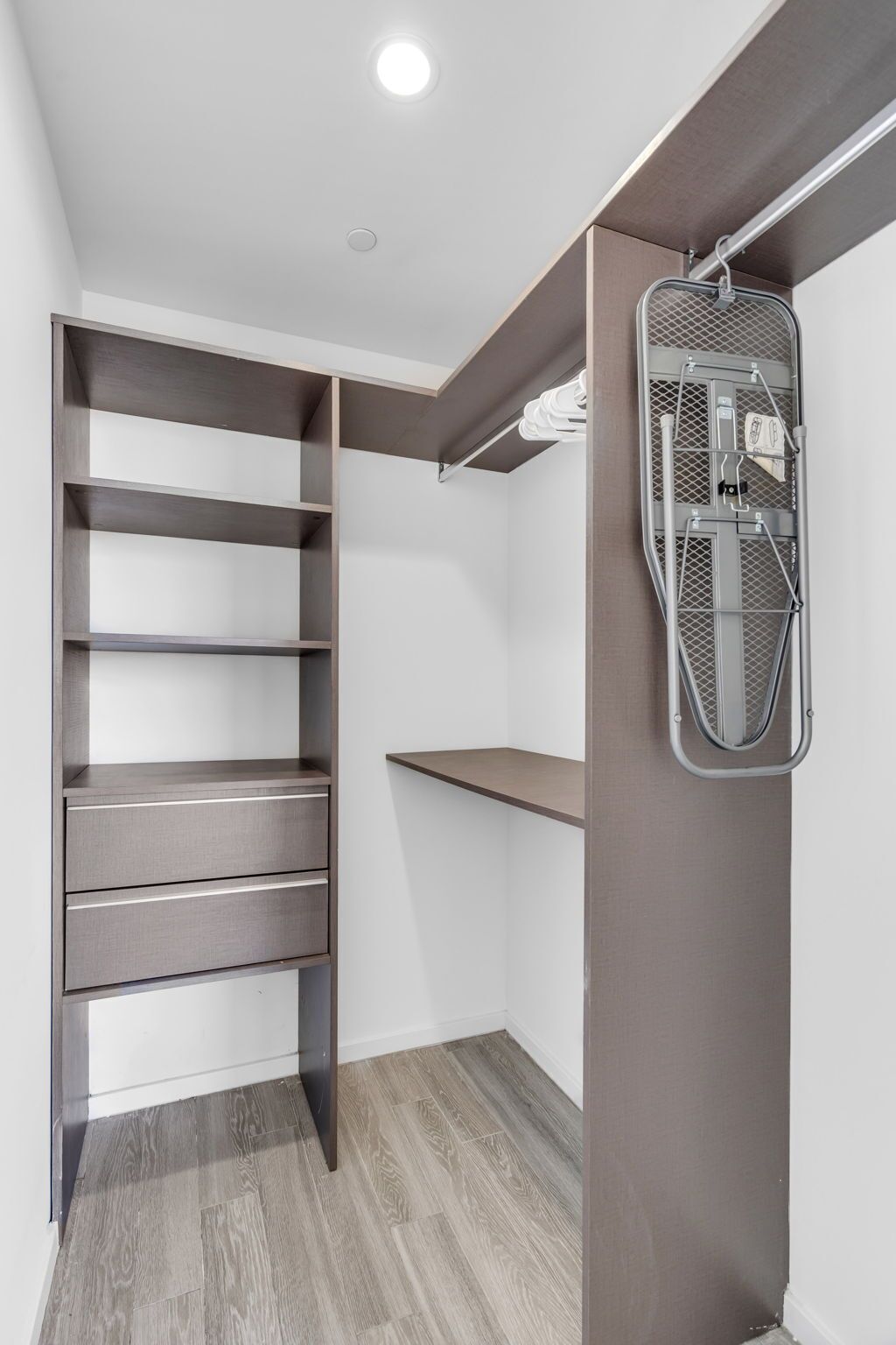 A walk-in closet with open shelving, a hanging rack, and a wooden floor.