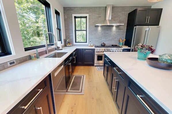 A modern kitchen with a central island, stainless steel appliances, and a view of the outdoors.