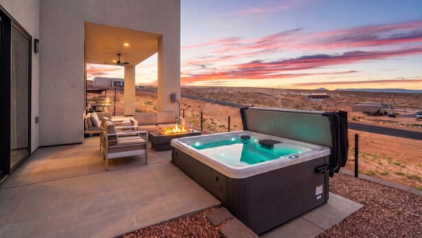 Un patio moderno al aire libre con un jacuzzi, zona de estar y vistas al paisaje desértico.