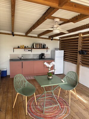 A kitchen with wooden beams, a refrigerator, a coffee maker, and a shelf with kitchen items. - Unique Bungalow for 2 People in KA CLAUDINE, SAINT FRANÇOIS (Saint-François)