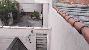 Una scala conduce a una terrazza con vista su un cortile e un edificio sullo sfondo.