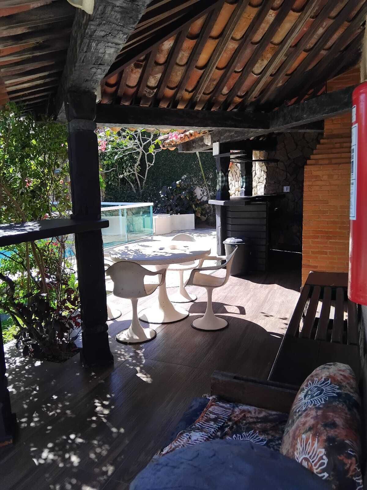Un patio esterno con un muro in pietra, un soffitto in legno e una zona salotto con sedie bianche.