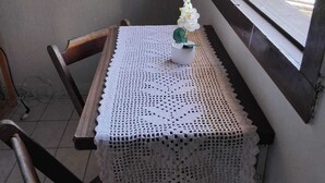 Un tavolo con una tovaglia all'uncinetto, un'orchidea in vaso e una finestra con vista sugli edifici.