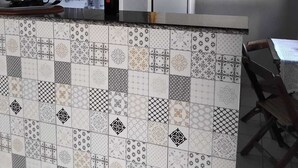 Una cucina con piastrelle a parete, una macchina per il caffè, un lavello e un frigorifero.