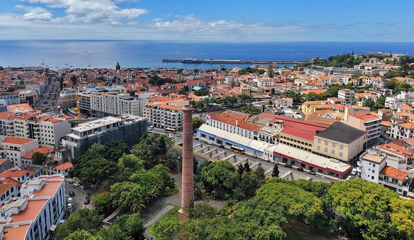 Ein Küsten-Stadtbild mit einem markanten Turm, dichten Gebäuden und freiem Blick auf das Meer.