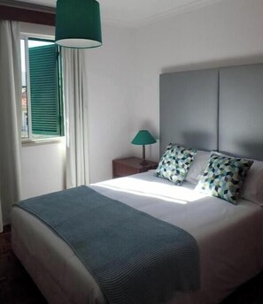 Ein Hotelzimmer mit Bett, Nachttischlampe und einem fenster mit Vorhängen.