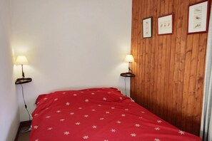 Ein Zimmer mit einem Bett, zwei Nachttischlampen, einer Holzvertäfelung und drei gerahmten Bildern.