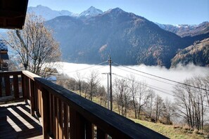 Eine Holzterrasse mit Blick über ein Tal, im Hintergrund Berge.