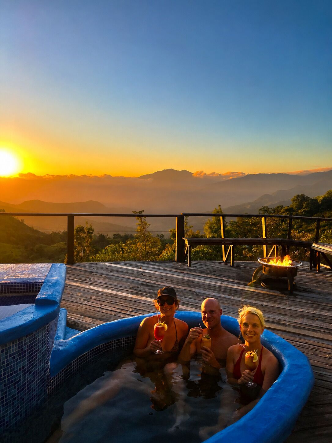 Un bain à remous sur une terrasse en bois, avec vue sur les montagnes au coucher du soleil.