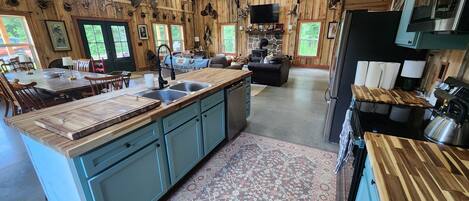 Une cuisine rustique avec des meubles en bois, un grand îlot central et une cheminée en pierre.
