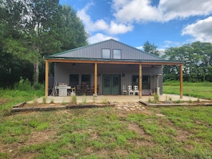A rustic cabin with a covered porch, a grill, and outdoor seating. - Yellowhammer Lodge near Lake Weiss and Little River Canyon (Gaylesville)