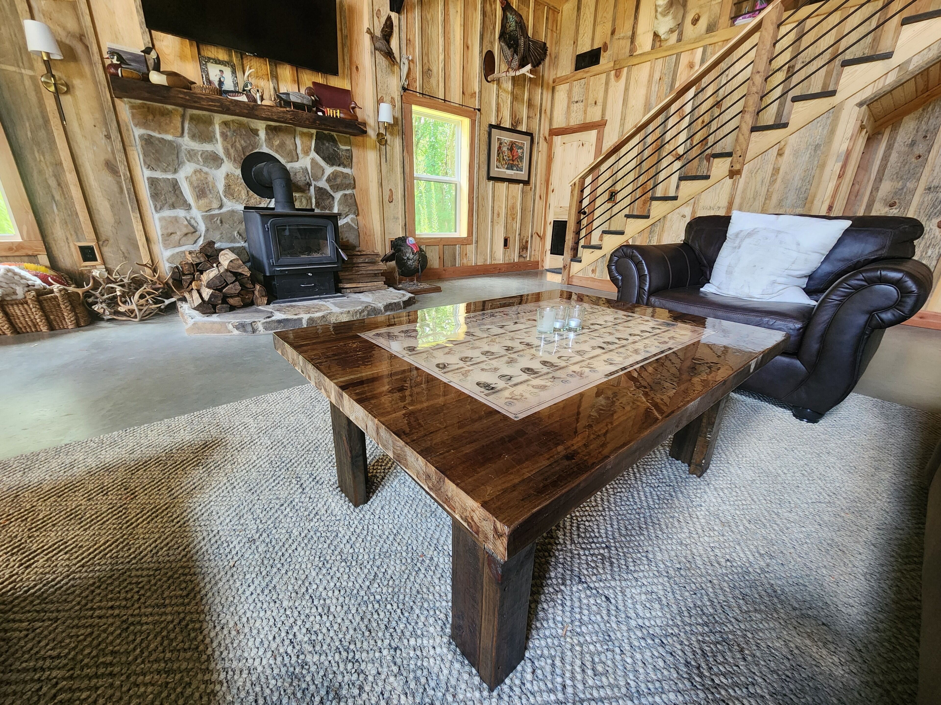 A rustic interior with a stone fireplace, wooden walls, a leather sofa, and a coffee table.