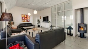 Un salon moderne comprenant un canapé, une table basse, un téléviseur, une cheminée et des œuvres d’art.