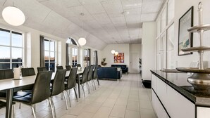 Une cuisine moderne avec des meubles blancs, un plan de travail noir et un coin repas comprenant des chaises et des tables.