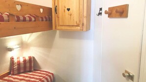 Ein kleiner, gemütlicher Raum mit einem Etagenbett, einem Holzschrank mit Herzformen und einer Tür mit einem Holzzugknopf.