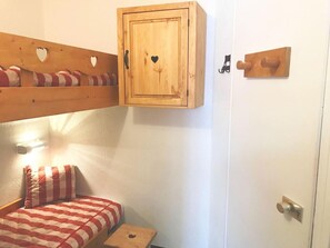 A small, cozy room with a bunk bed, a wooden cabinet with heart-shaped cutouts, and a door with a wooden handle. - 100m from ski slopes, 2nd floor, balcony, tv, ski locker, 28m², Les Arcs (Les Arcs)