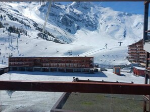 Une station de ski avec un bâtiment en bois, des remontées mécaniques et une montagne enneigée en toile de fond.