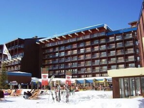 A multi-story hotel with balconies, a ski slope in the foreground, and a clear blue sky. - 100m from ski slopes, 2nd floor, balcony, tv, ski locker, 28m², Les Arcs (Les Arcs)